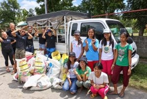Volunteers and local students with bags of rubbish collected on International Coastal Cleanup Day