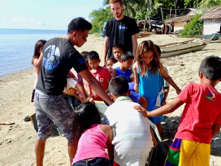 An MCP staff member with a group of local children on the beach