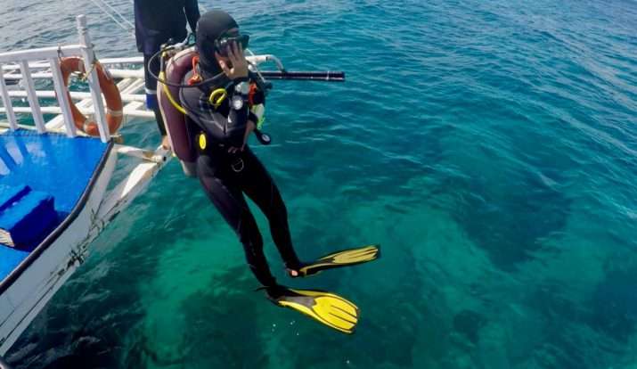 Diver descending from a boat into clear turquoise water