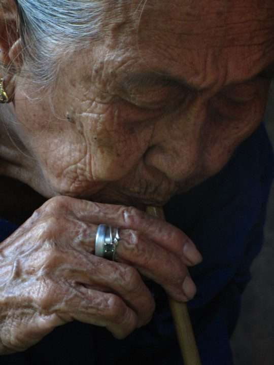 Elderly folk healer from Siquijor blowing through a wooden straw