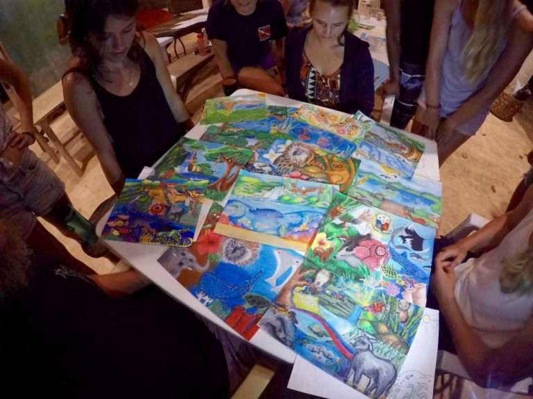 Volunteers looking at a table covered in colourful hand-painted marine postcards