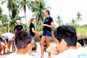 A volunteer talking with local children outdoors during a community education activity