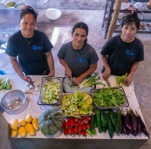 MCP's kitchen staff smiling behind a table full of fresh vegetables