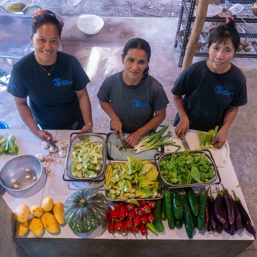 MCP's kitchen team smiling behind a table of fresh vegetables