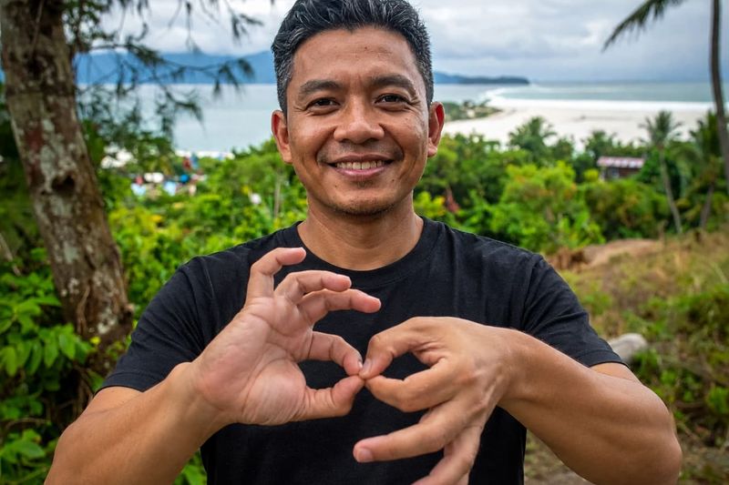MCP team member making a heart sign with his hands by the sea